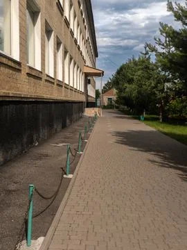 Paving path with green pillars in front of a brick building Stock-Fotos