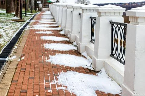 Paving paths in the park, covered with the first snow in winter. Stock Photos