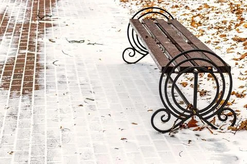 Paving paths in the park, covered with the first snow in winter. Stock Photos