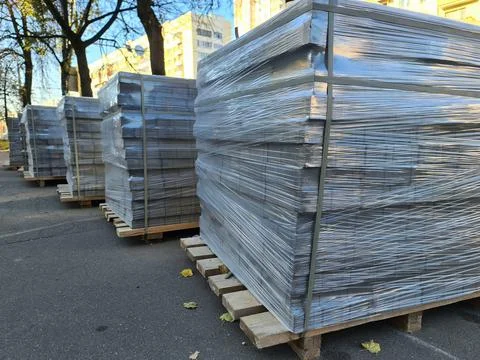 Paving slabs in plastic wrap lying on wooden pallet in street Stock Photos