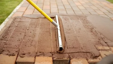 Paving Stone Jointing Process. Video shows worker applying and spreading sa.. Stock Photos