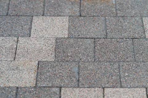 Paving stones are arranged in a pattern on a walkway in a town square. The st Stock Photos