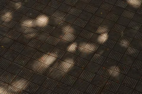 Paving stones creating geometric pattern with sunlight and shadows Stock Photos