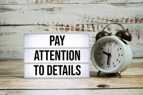 Pay Attention To Details text on light box with alarm clock on wooden backg.. Stock Photos