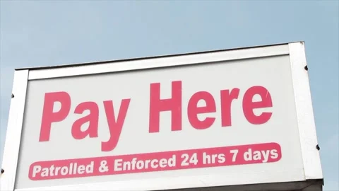 Pay here patrolled and enforced 24 hours 7 days rectangle sign above pay meter Stock Footage 248712972