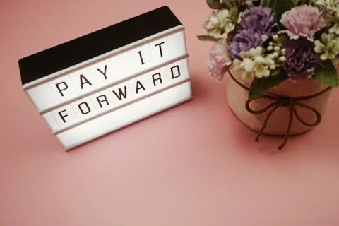 Pay It Forward word in light box with space copy on pink background Stock Photos