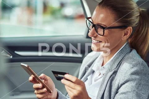 Pay online. Happy middle aged business woman using her smartphone and credit Stock Photos
