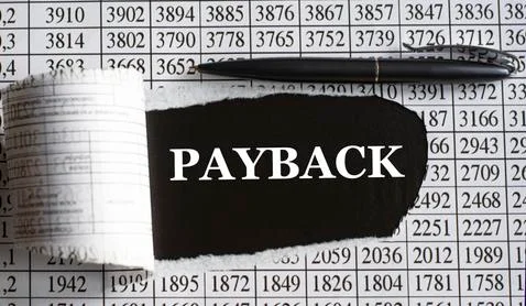 PAYBACK is the word behind torn office paper with numbers and a black pen. Stock Photos