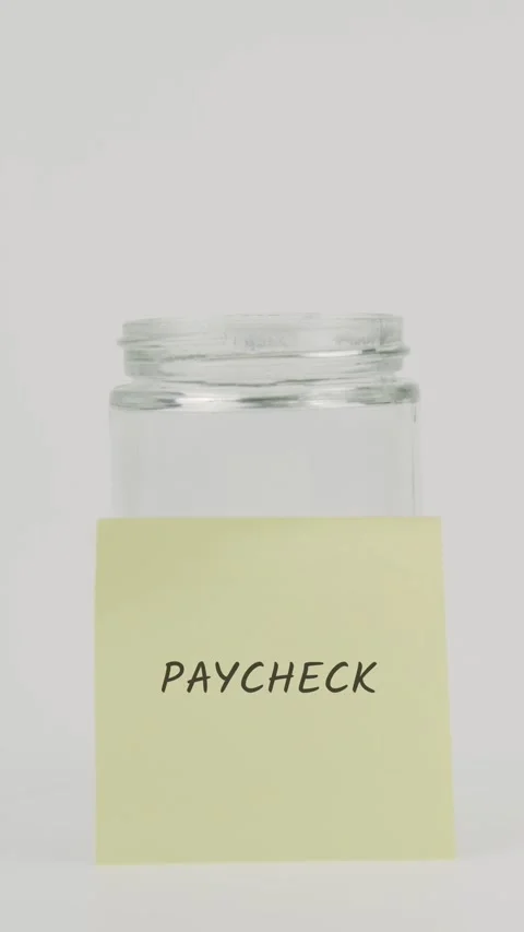 Paycheck text or word on yellow sticky note attached to glass jar with hand Stock Footage 311764861