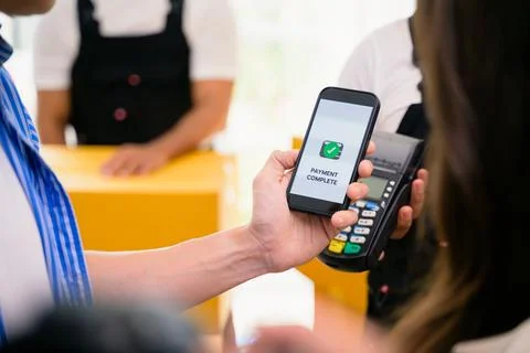 Payment completed message on mobile phone screen, Young man and woman paying for Stock Photos