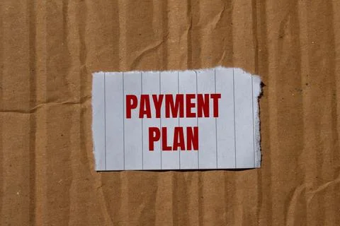 Payment plan message written on ripped torn paper with cardboard background.  Fotos Stock