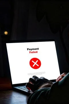 Payment process shows a failed status on a laptop screen in a dimly lit room Stock Photos