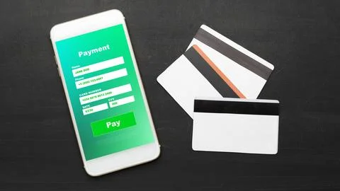 Payment process using a mobile phone and credit cards on a black surface in an Stock Photos