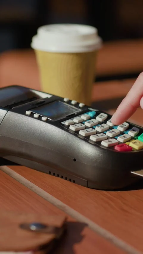 A Payment Terminal placed conveniently on a Table accompanied by Coffee and a Video stock 305945801