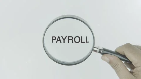 Payroll text or word highlighted by a magnifying glass in a hand on a white Stock Footage 303684698