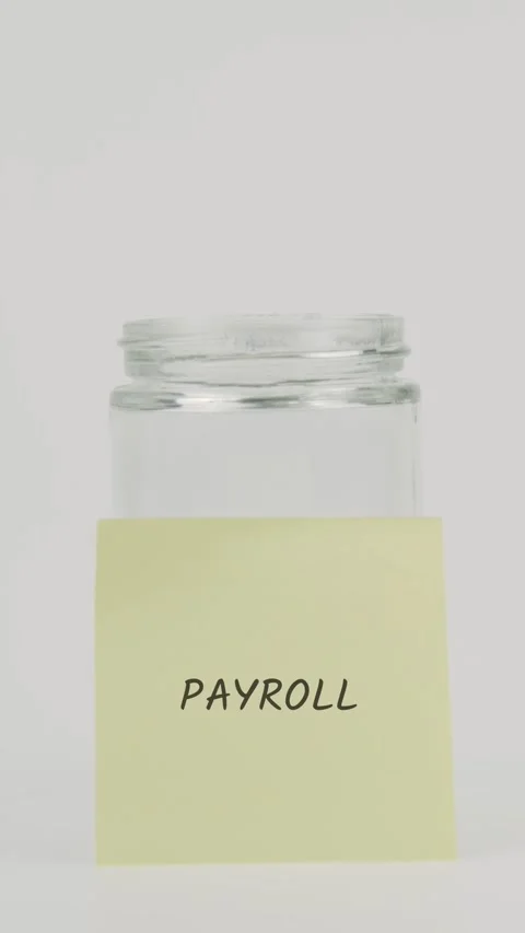 Payroll text or word on yellow sticky note attached to glass jar with hand Stock Footage 311765247