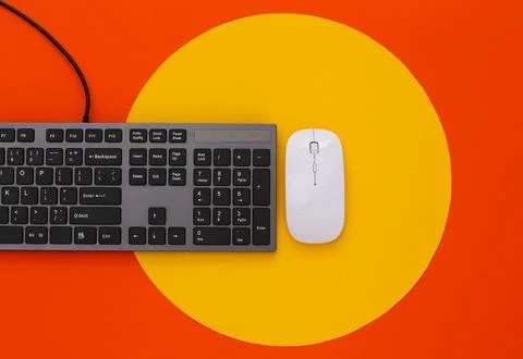 PC keyboard and pc mouse on orange background with yellow circle. Top view Stock Photos