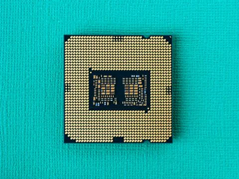 Pc micro CPU with gold plated contacts on a textured turquoise background. Stock Photos