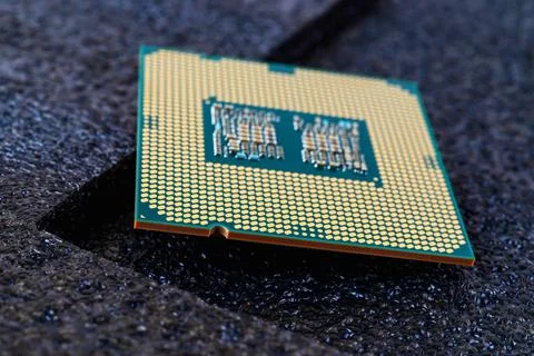 Pc micro CPU with gold plated contacts on a textured dark background. Stock Photos