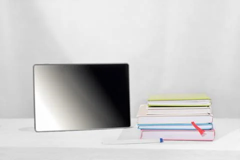 Pc tablet next to a stack of books and a pen on a table. study and learning,  Stock Photos