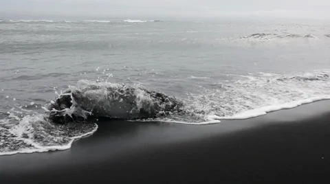 Peace of ice being washed by waves at the black sand beach, Iceland Stock Footage 33778482