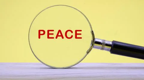 Peace text on a yellow background through a magnifying glass Stock Photos