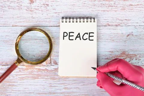PEACE writing on a notebook lying on old boards next to a magnifying glass an Stock Illustration