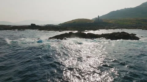 Peaceful aquatic perspective of a distant lighthouse standing watch over rocky Vídeo Stock 336286798