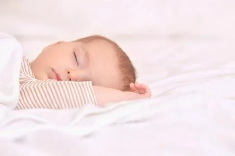 Peaceful baby lying on a bed while sleeping in a bright room Stock Photos