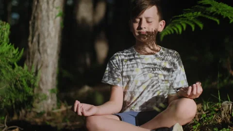 Peaceful Boy meditating sitting  in forest in nature Stock Footage