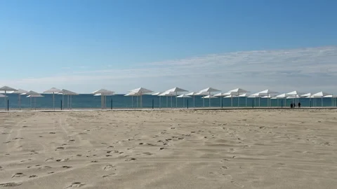 A peaceful, empty beach with pristine white sand and rows of white umbrellas und Stock Footage 310839531
