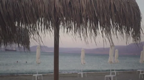 Peaceful empty beach with straw umbrellas in the evening. Pastel colors Stock Footage 67676093