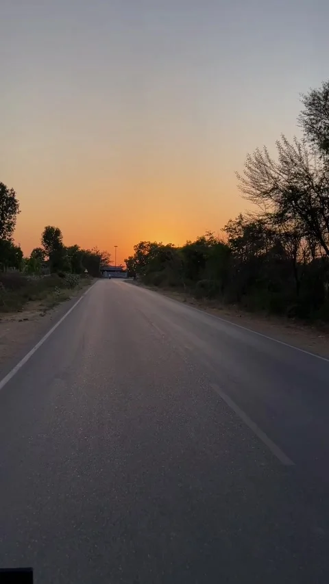 Peaceful evening view of a rural highway surrounded by silhouetted trees at dusk 스톡 동영상 333451553