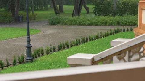 Peaceful Garden Pathway in Light Rain Seen from Elegant Terrace Stock Footage 345234758