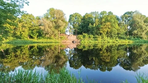 Peaceful lake reflection with trees and small boat in summer setting Stock Footage 314302752