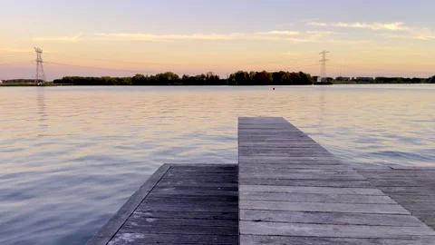 Peaceful lake view with deck at sunset with clear sky, 4K realtime video Video stock 251885210