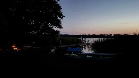 Peaceful Lakeside Evening with Fire and Boats at Sunset Stock Footage 282277778