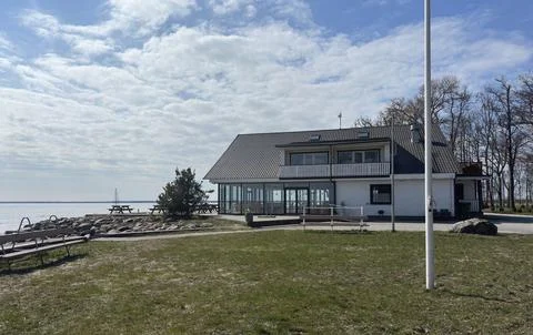 A peaceful lakeside view featuring a two-story white house with large windows Stock Photos