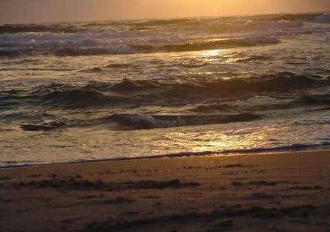 Peaceful low angle view of a sandy beach at sunset with small waves 写真素材