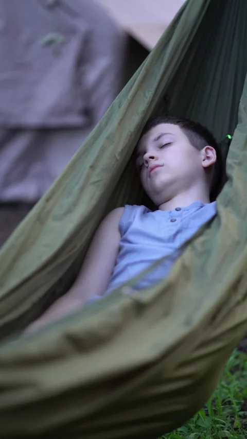 Peaceful moment of a kid napping in a hammock in the woods on a sunny day. Stock Footage 342179402