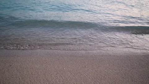 Peaceful ocean surface, calm teal waves gently roll onto the sandy shore Stock Footage 310311018