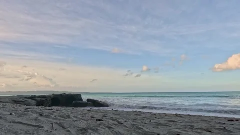Peaceful Ocean Waves Washing onto Sandy Beach with Rocks at Sunset Stock Footage 340413880