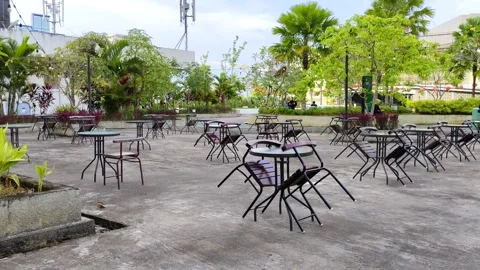 A peaceful outdoor cafe area with empty tables and chairs Stock Footage 302370751