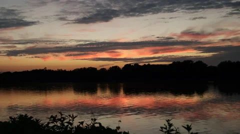 Peaceful river flowing in front of orange sunset Stock Footage 53038359