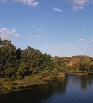 Peaceful River Scene with Trees Under Clear Sky Stock Photos