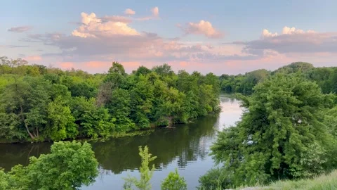 A peaceful river surrounded by lush green trees, reflecting the soft pastel. Vidéo 302394732