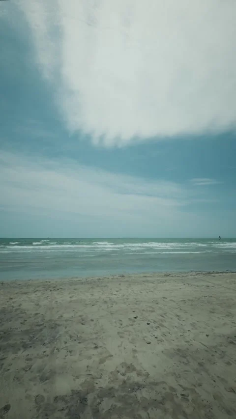 Peaceful sandy beach with gentle ocean waves and cloudy sky 库存影片 346275052