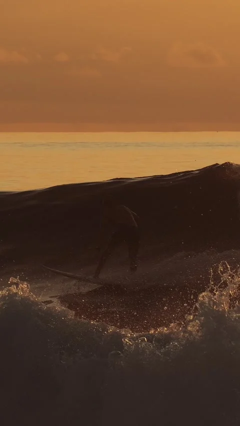 Peaceful seaside setting capturing lone surfer amidst shimmering waves at dusk Stock Footage 321988385