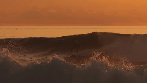 Peaceful seaside setting capturing lone surfer amidst shimmering waves at dusk Stock Footage 321988414