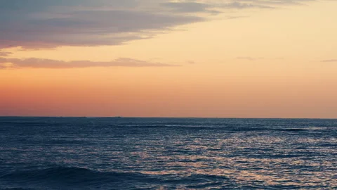 Peaceful slow motion waves glowing under warm sunset sky Stock-Footage 343380337